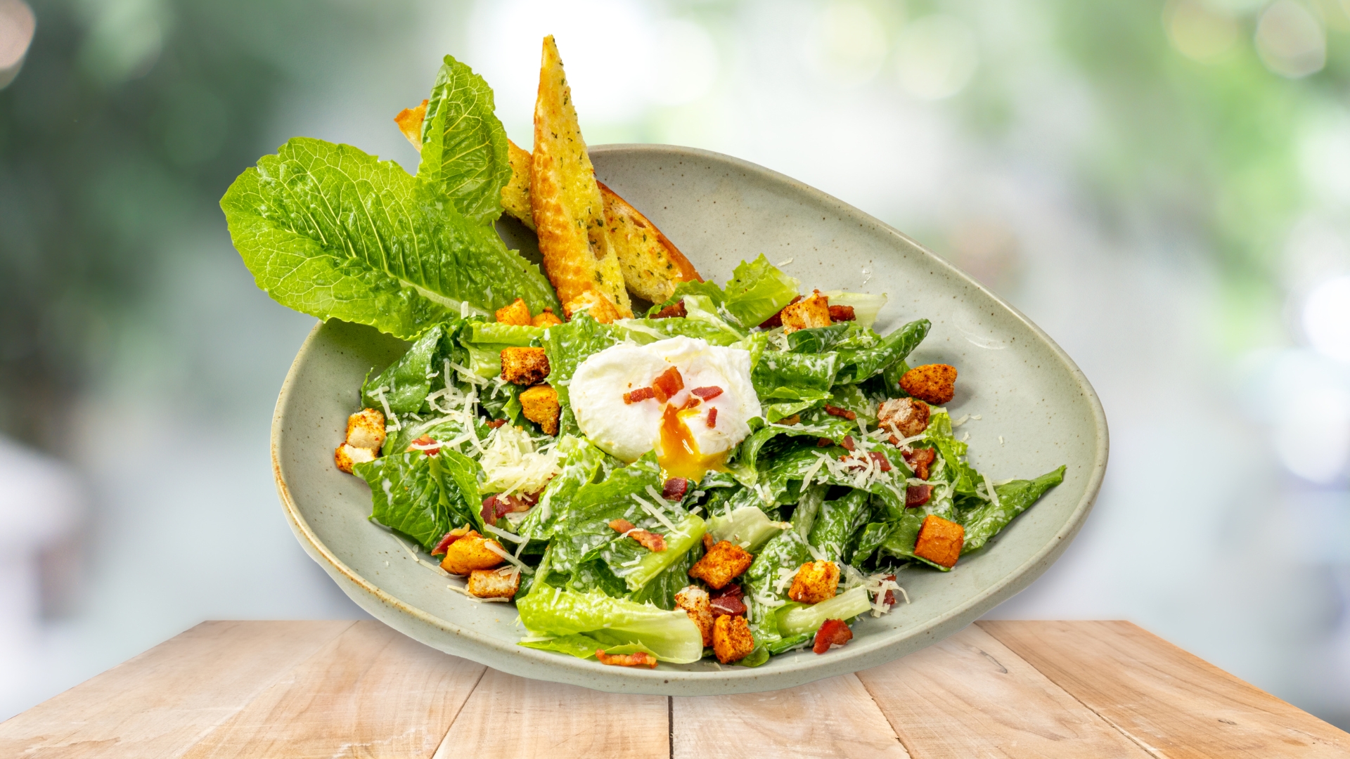 Caesar Salad kết hợp xà lách Romaine, bánh mỳ nướng, thịt ba chỉ xông khói, trứng chần và Parmesan.