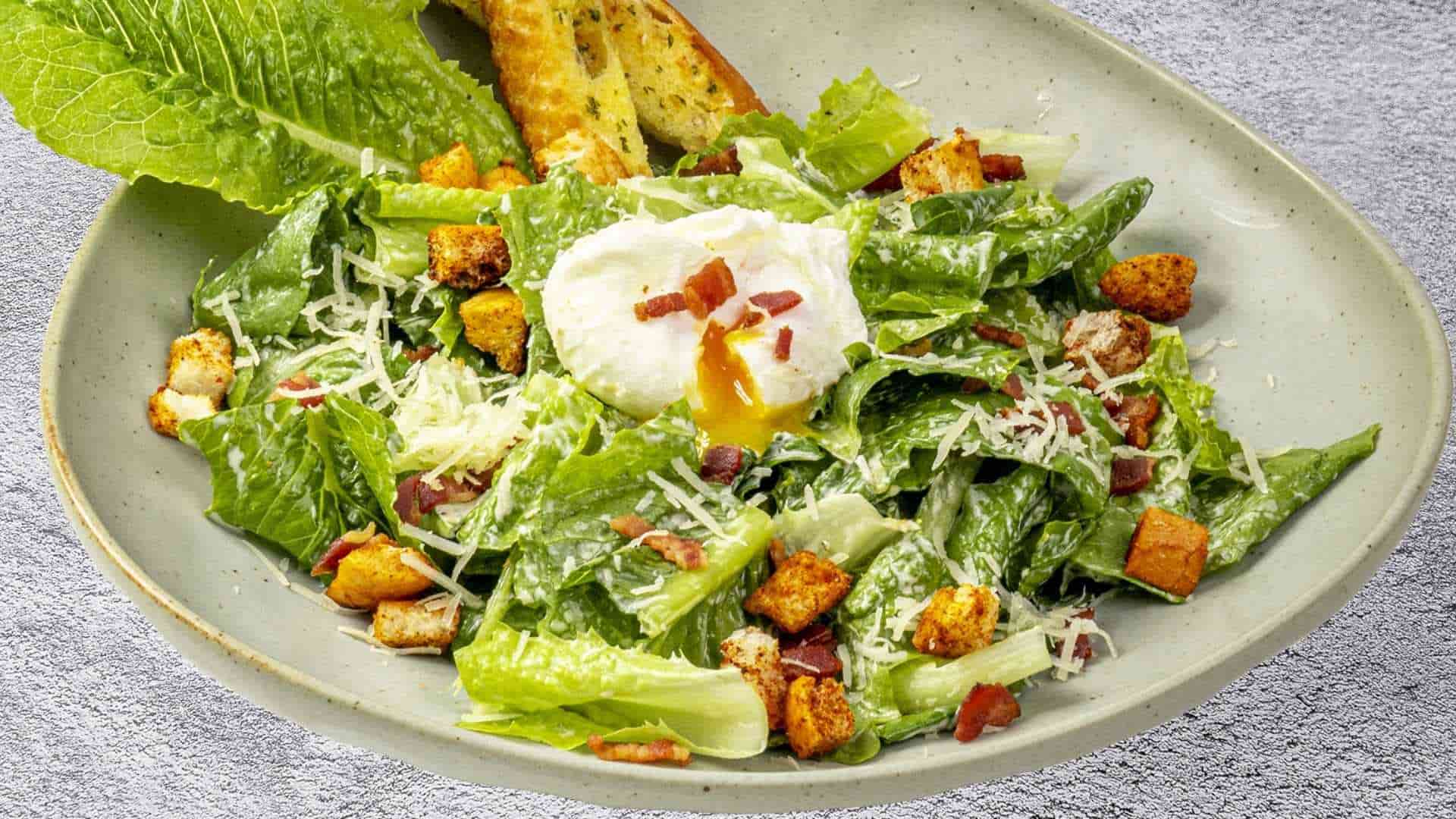 Caesar salad thanh mát với xà lách giòn, phô mai Parmesan và xốt béo nhẹ, món ăn kèm hoàn hảo cho pizza