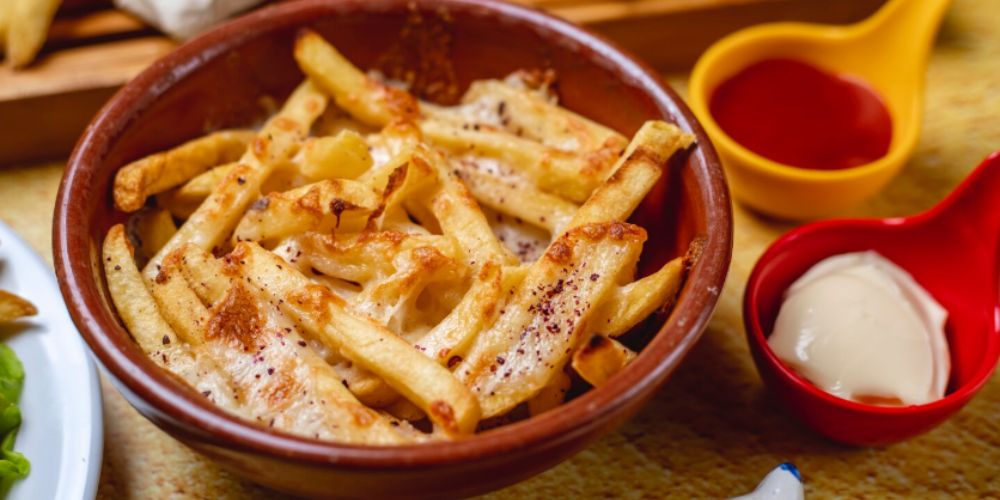 Rắc phô mai Parmesan bào sợi cùng chút tiêu đen lên khoai tây chiên còn nóng