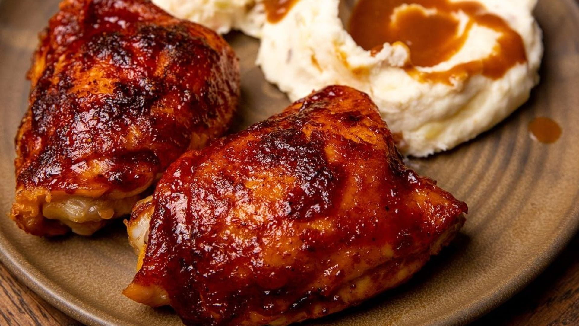 Má đùi gà chiên xốt BBQ được phủ đều xốt BBQ, dùng nóng cùng khoai tây chiên hoặc rau củ tùy thích.